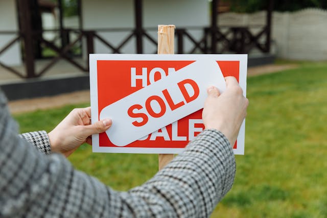 A real estate agent posting a sold sign on a house